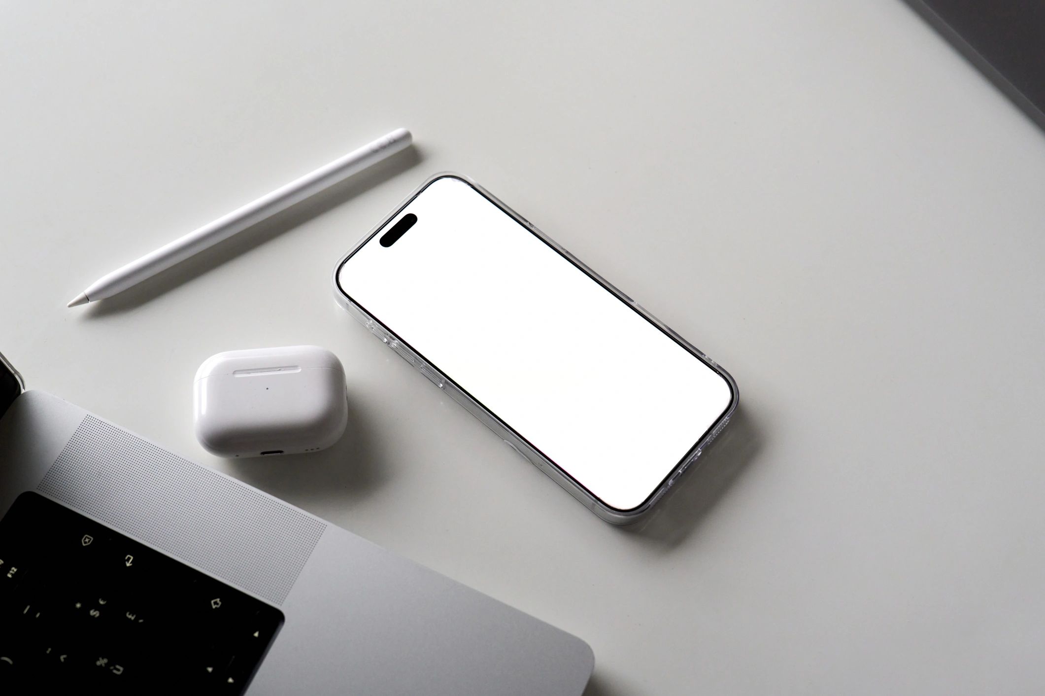 Smartphone with earbuds and laptop on a desktop